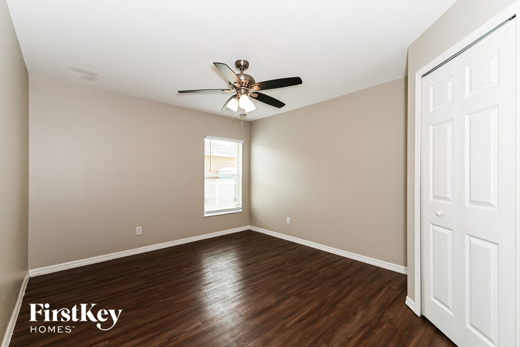 A room with a ceiling fan and wooden floors.