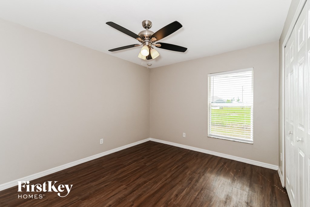 A room with a ceiling fan and a window with blinds.