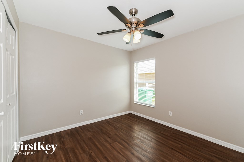 A room with a ceiling fan and wooden flooring.
