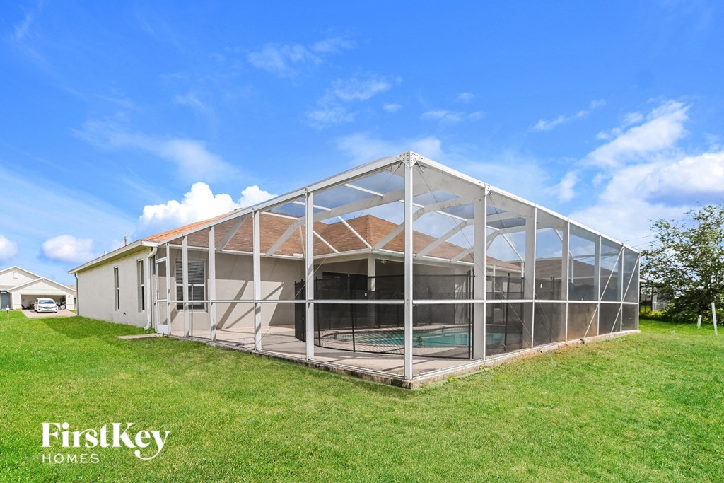 A large, white, metal-framed building with a glass wall and a brown roof.