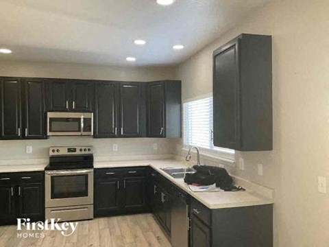 A kitchen with black cabinets and a stainless steel oven.