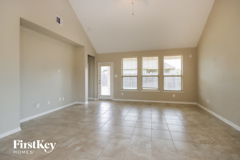 an empty living room with windows and tile floors