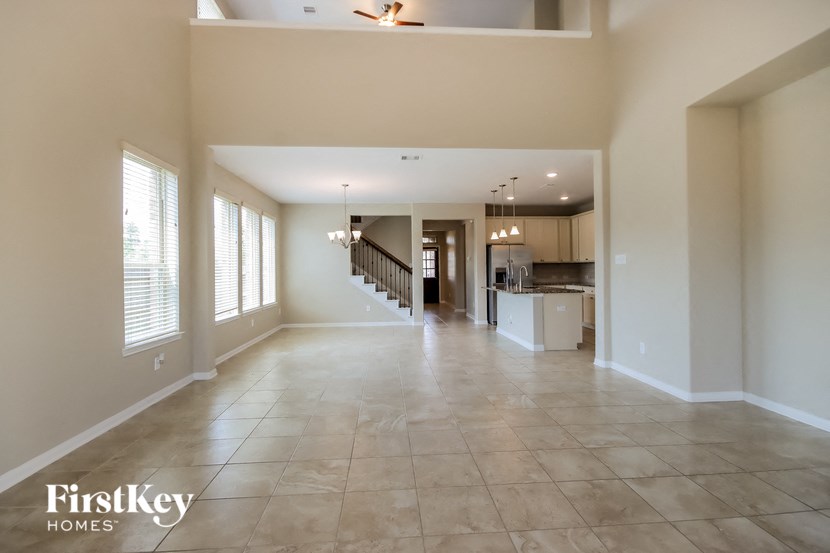 an empty living room with a kitchen and a staircase