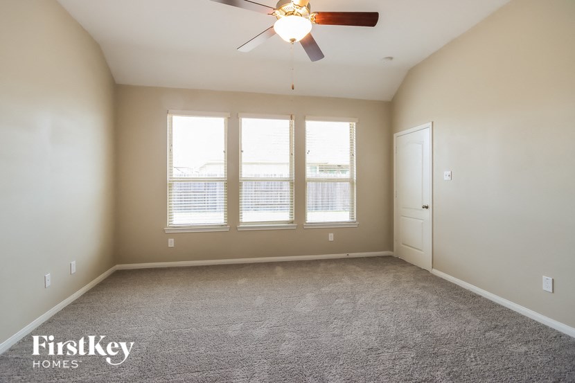 an empty room with a ceiling fan and three windows