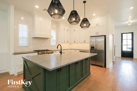 a kitchen with green island and white cabinets and stainless steel appliances