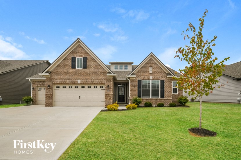 front view of a brick house with a lawn and a driveway