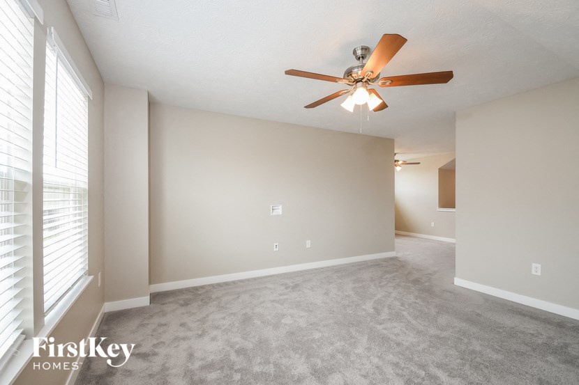an empty living room with a ceiling fan and a large window