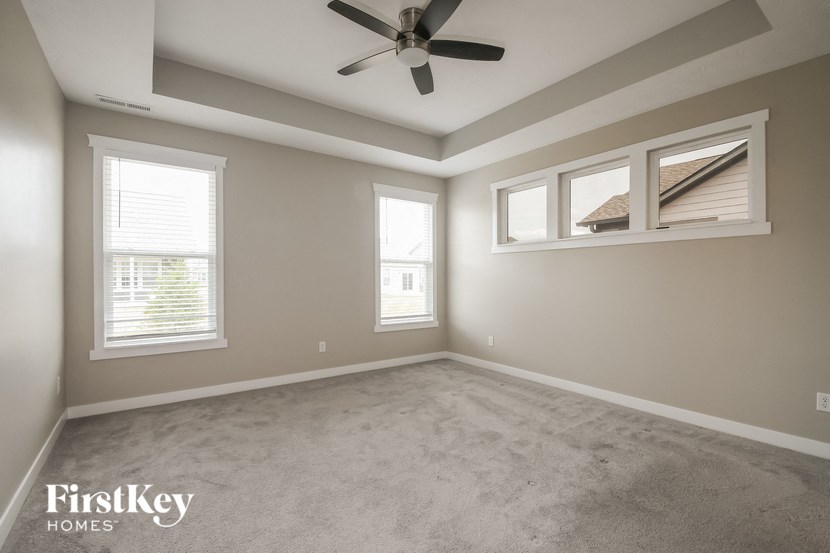 an empty room with a ceiling fan and three windows
