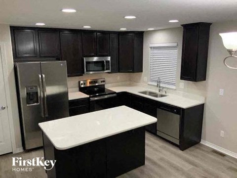 a kitchen with black cabinets and a stainless steel refrigerator