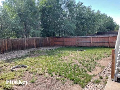 a backyard with a fence and grass and trees