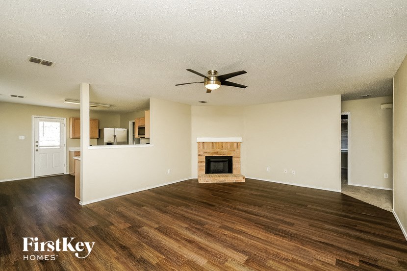 an empty living room with a fireplace and a ceiling fan