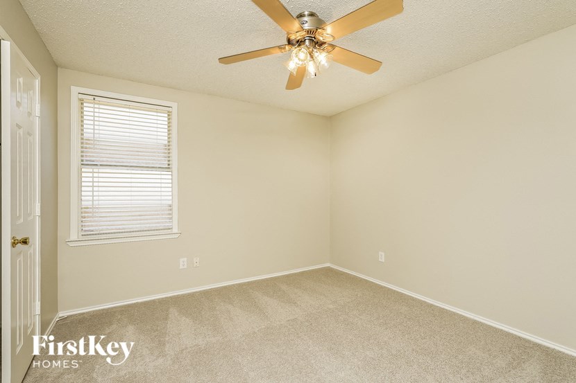 an empty bedroom with a ceiling fan and a window