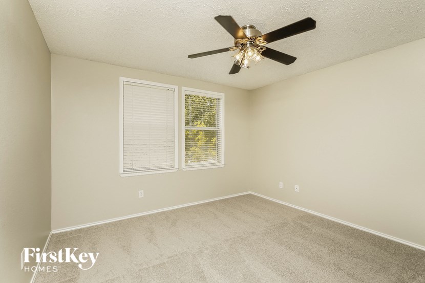 an empty room with a ceiling fan and a window