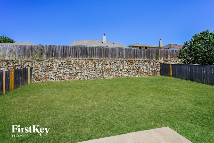 a backyard with a grass lawn and a stone wall