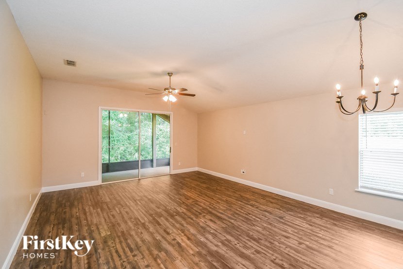 the living room of an empty house with wood flooring and a ceiling fan