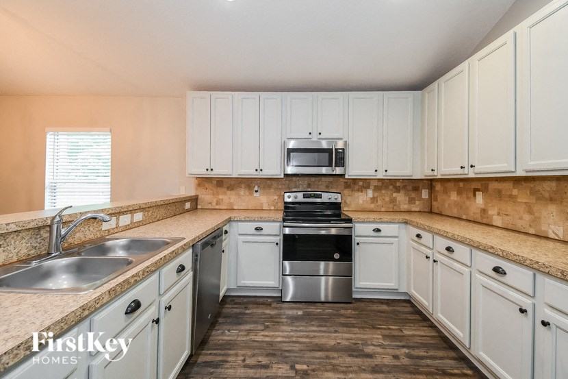 a kitchen with white cabinets and a sink and a stove