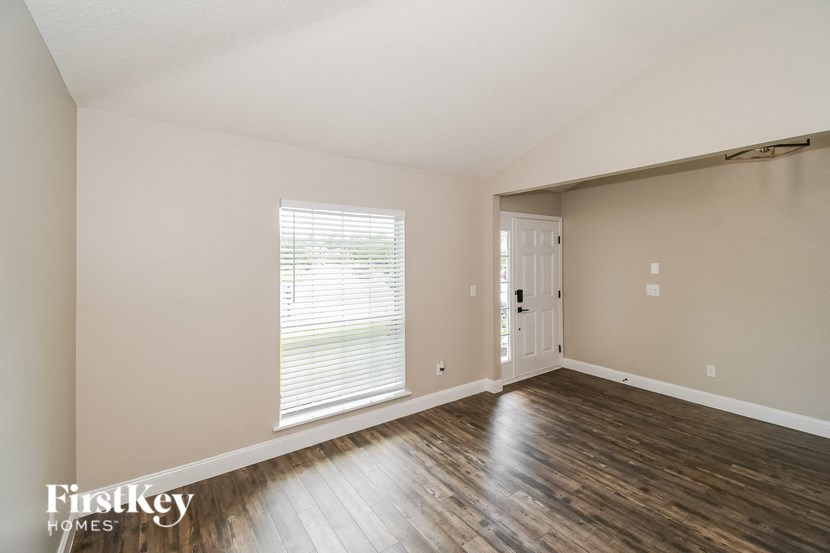 the living room of an apartment with wood flooring and a white door
