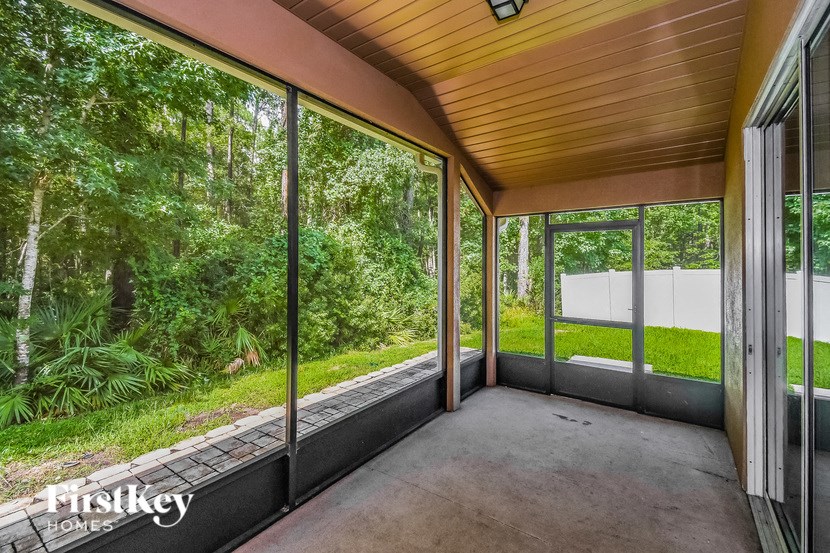 a screened porch with glass doors and a view of the woods