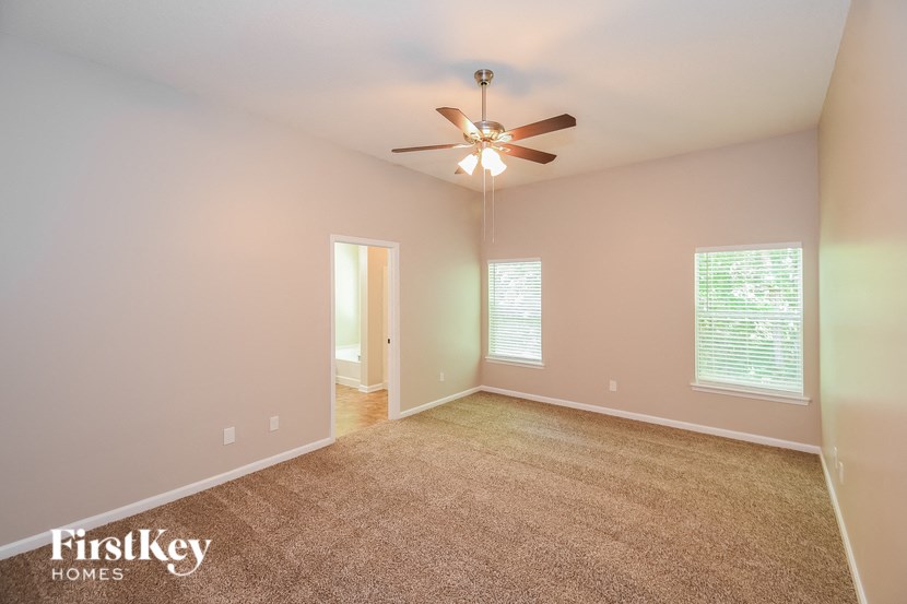 a living room with a ceiling fan and a carpet