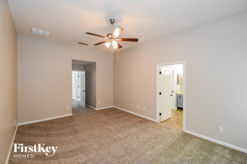 a spacious living room with carpet and a ceiling fan