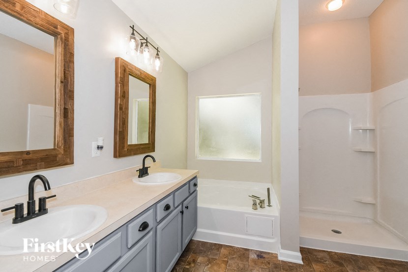 a bathroom with two sinks and a bath tub and a mirror