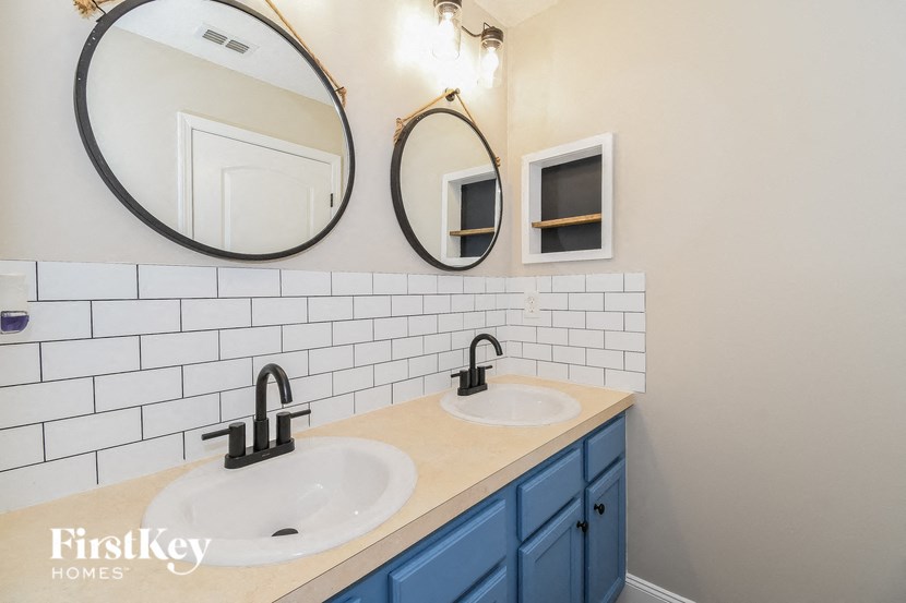two sinks in a bathroom with white subway tiles and two mirrors