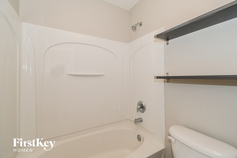 a white bathroom with a white toilet and a white bath tub