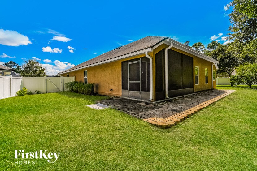a small yellow house with a lawn and a backyard