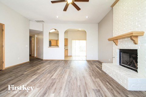 A spacious living room with a fireplace and a ceiling fan.
