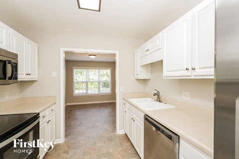 A kitchen with white cabinets and a stainless steel refrigerator.