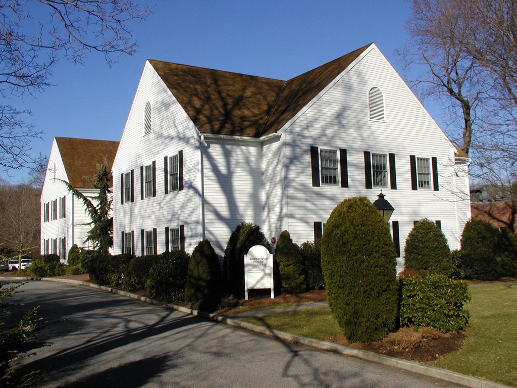 a white house with black shuttered windows and a driveway