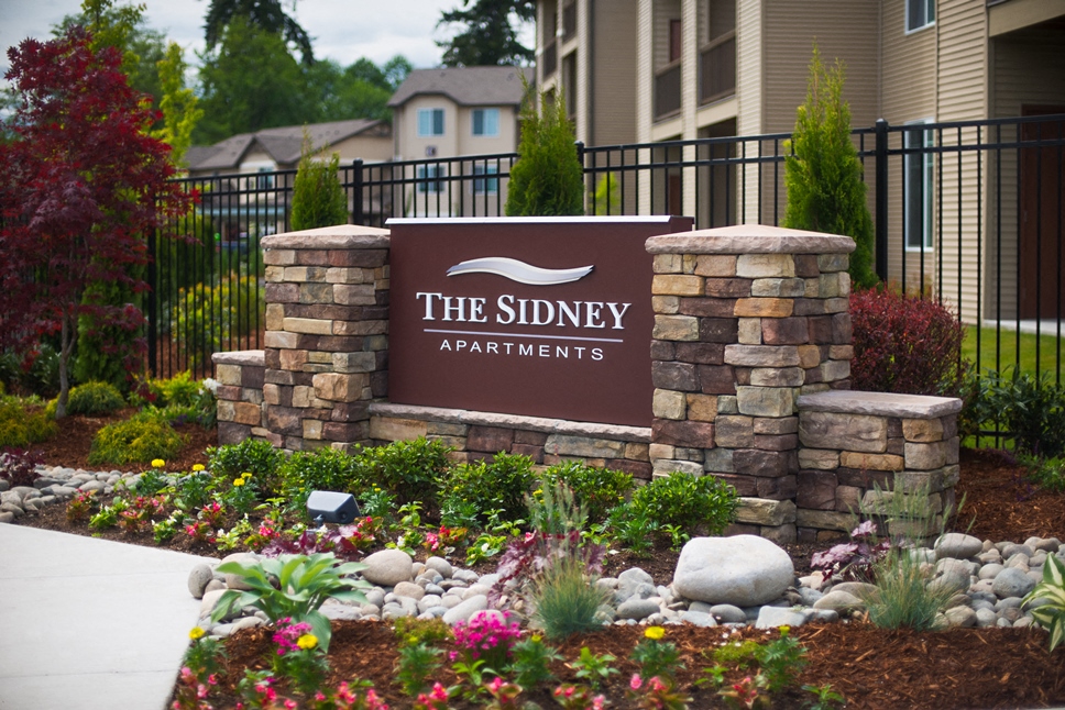 the sign at the siena apartments entrance sign in front of a stone wall
