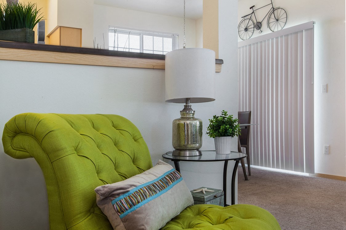 a living room with a green couch and a lamp