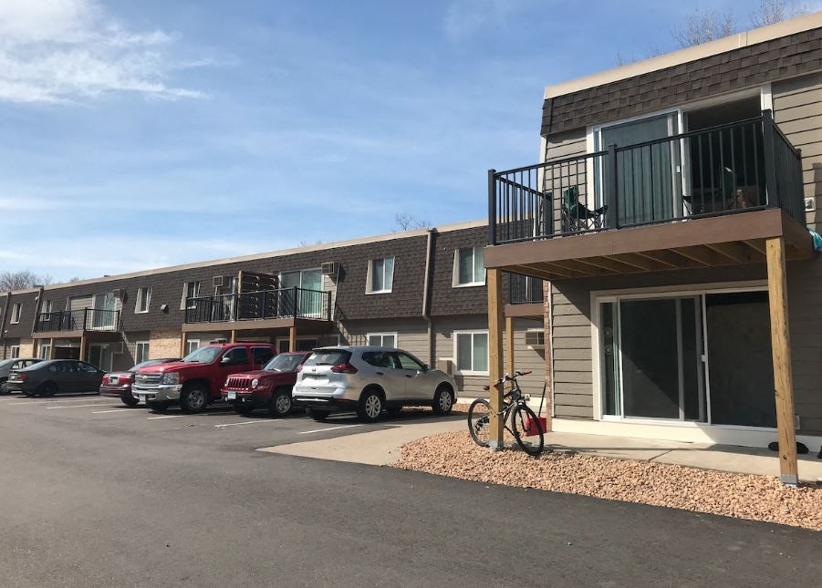 a bicycle parked in front of a building with cars parked in a parking lot