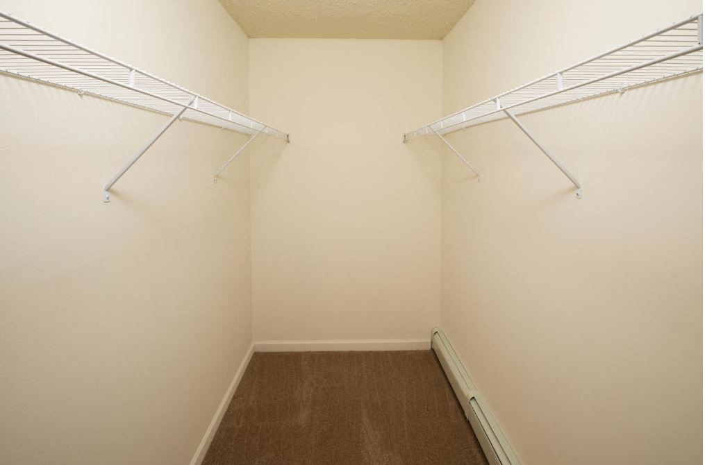 a walk in closet with two hanging racks on the wall