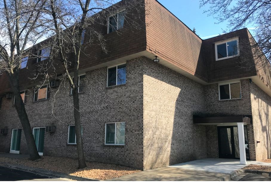 a brick building with a wooden roof and a sidewalk