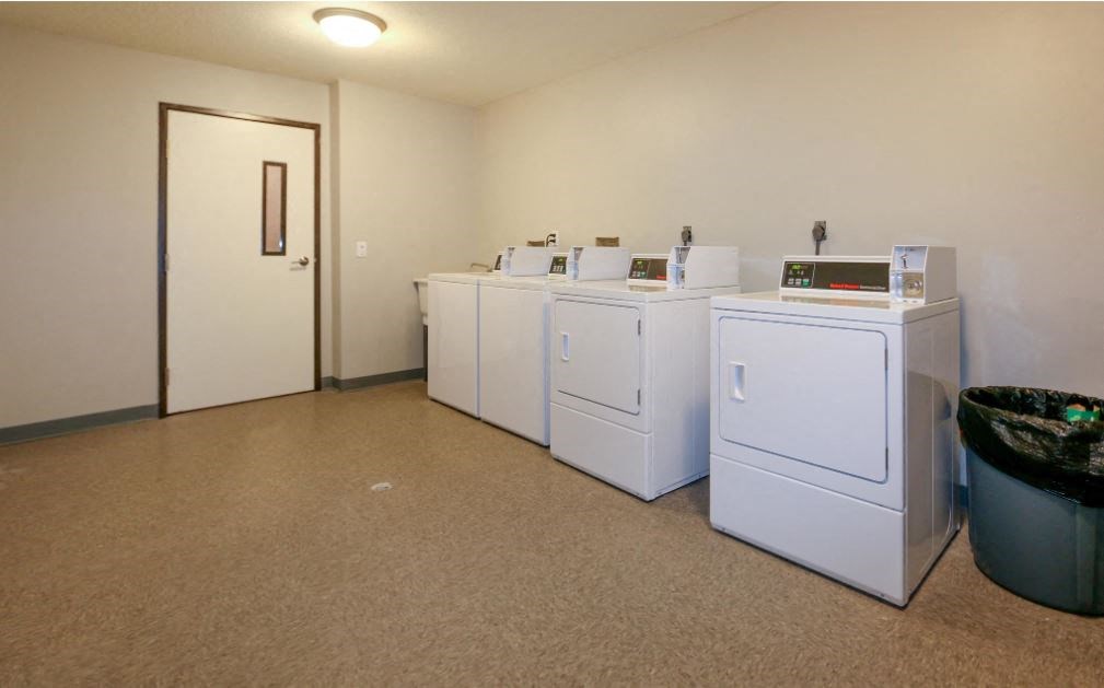 a room with four washing machines in it and a door