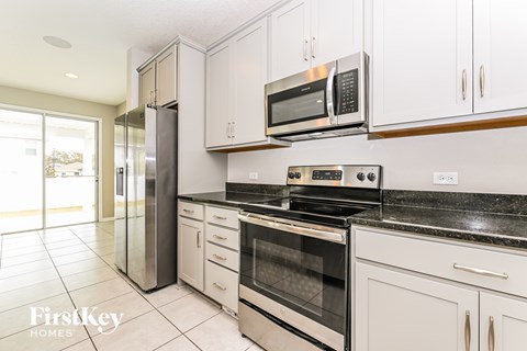 A kitchen with a stainless steel refrigerator, microwave, and oven.