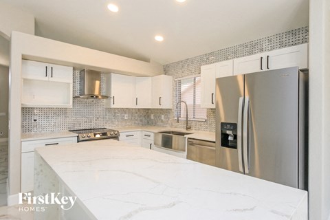 A kitchen with a stainless steel refrigerator and white countertops.