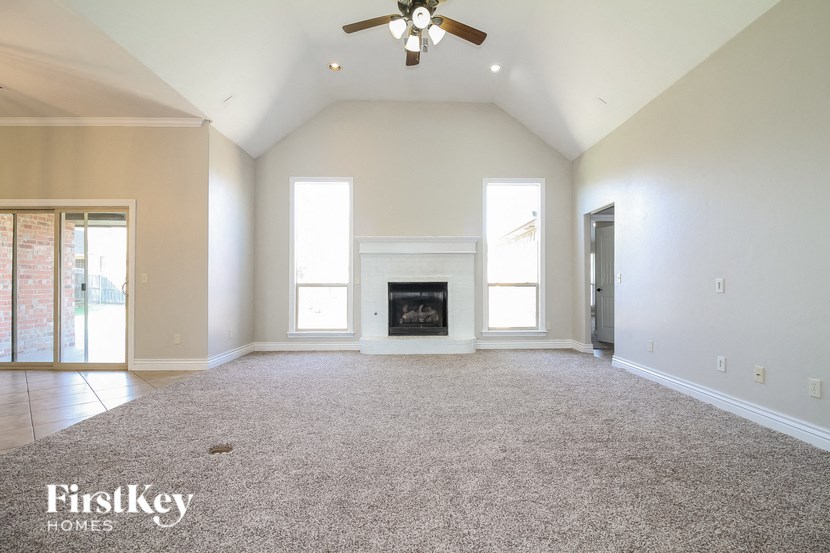 an empty living room with a fireplace and a ceiling fan