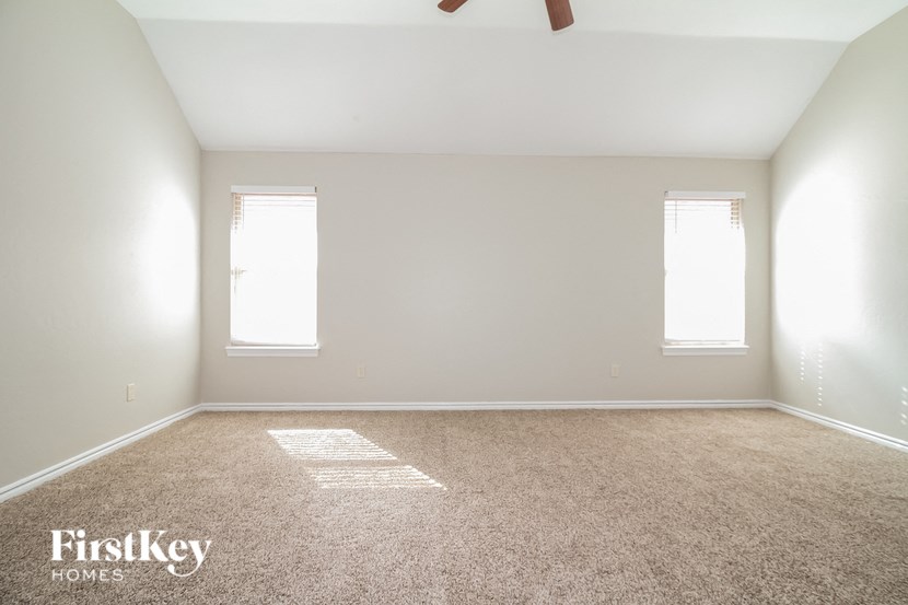 an empty room with two windows and a carpet