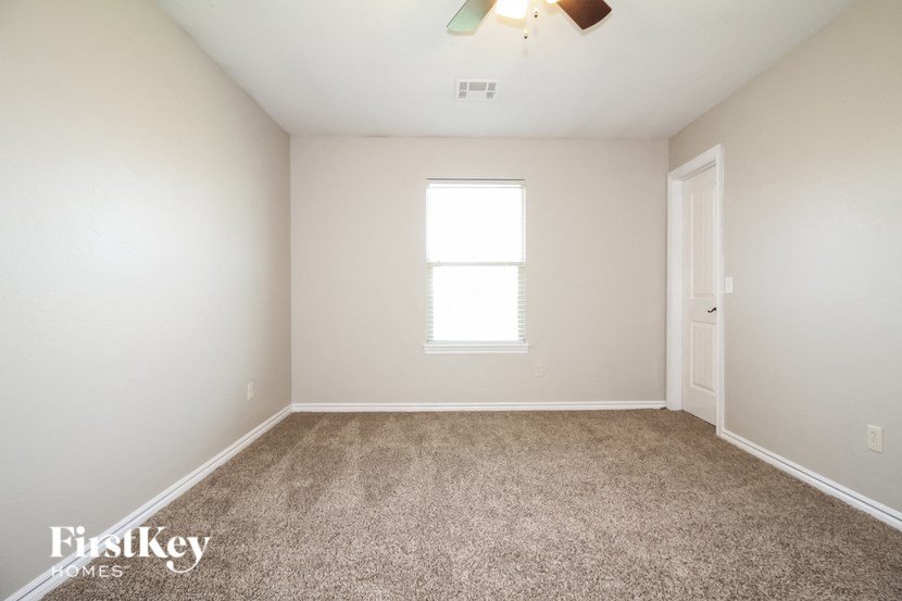 a carpeted room with a window and a ceiling fan