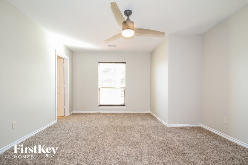 an empty room with a ceiling fan and a window