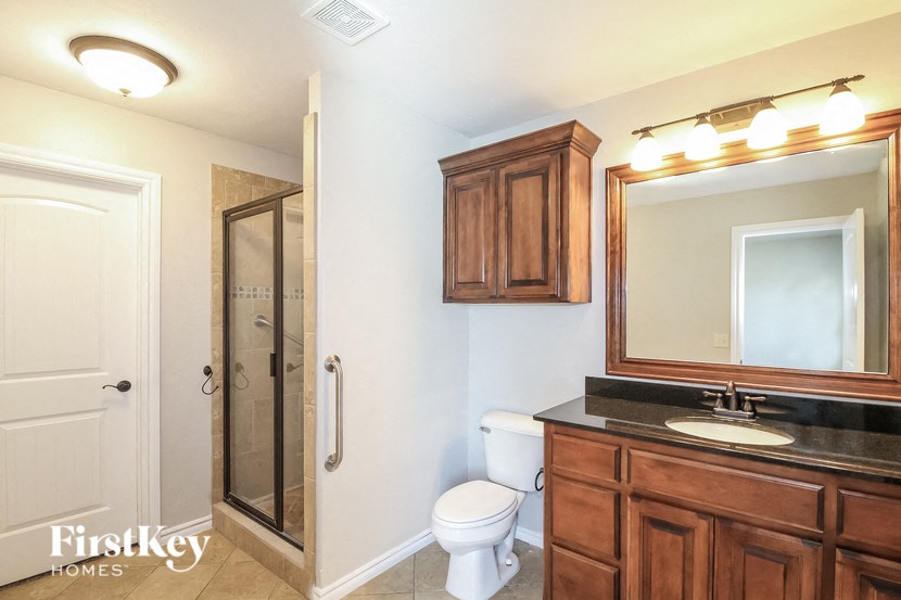 a bathroom with a toilet sink and mirror and a shower