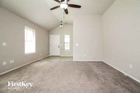 A spacious room with a ceiling fan and carpeted floor.