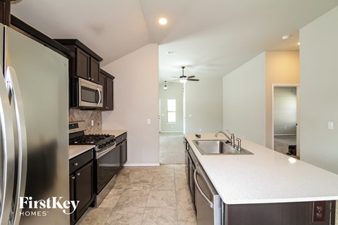 A kitchen with a refrigerator, microwave, and stove top oven.