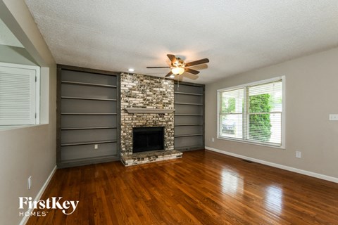 an empty living room with a fireplace and a ceiling fan