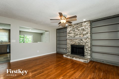 a living room with a stone fireplace and a ceiling fan