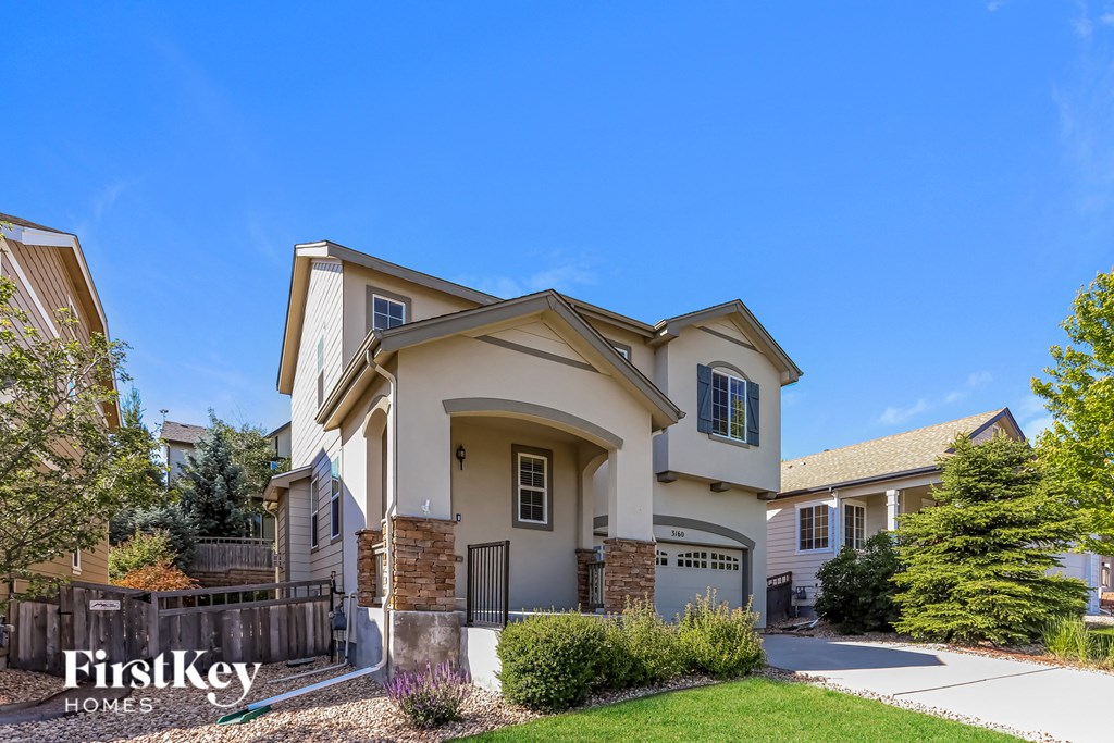 a beige house with a driveway and a fence