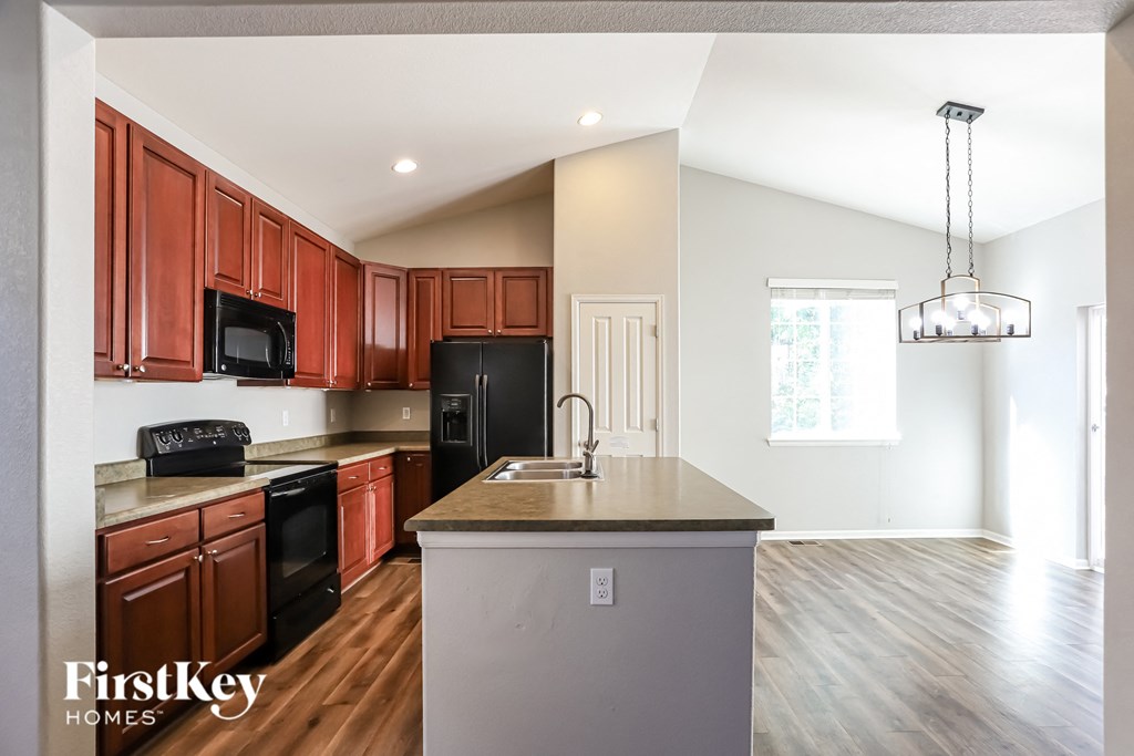 an empty kitchen with wooden cabinets and black appliances